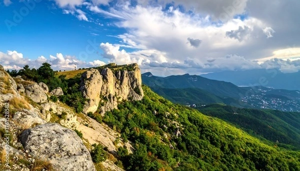 Obraz Mountain peak with rocky cliffs, lush green forests, and a partly cloudy sky