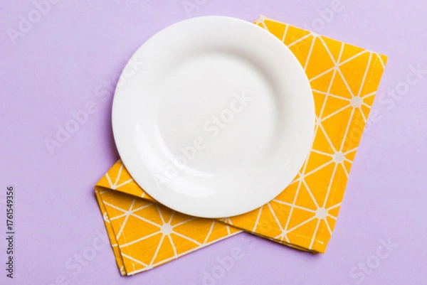 Obraz Top view on colored background empty round white plate on tablecloth for food. Empty dish on napkin with space for your design
