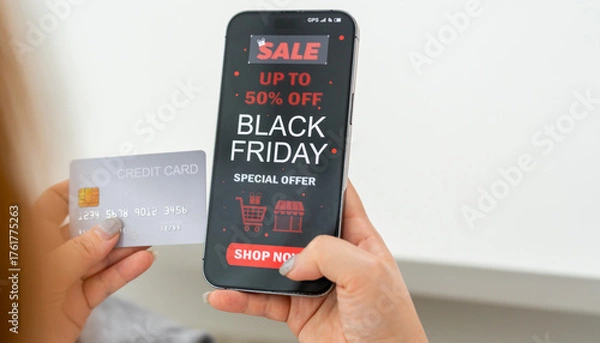Fototapeta Person using app shop online holding smartphone with Black Friday sale ad and credit card ready for online payment, e-commerce promotions, digital marketing, online shopping and mobile transactions