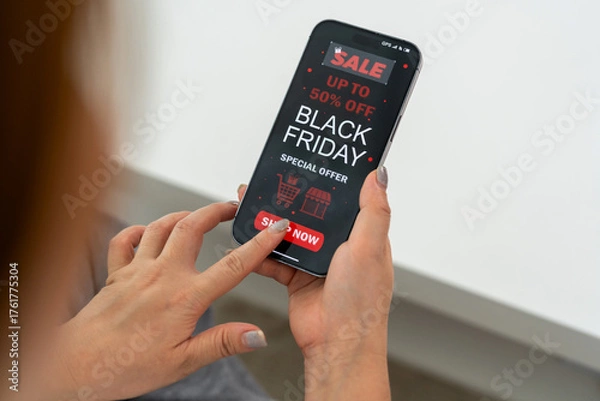 Fototapeta Person using mobile app shop online holding smartphone with Black Friday sale ad with up to 50% off, marketing and e-commerce promotions, holiday shopping, online deals and digital advertising