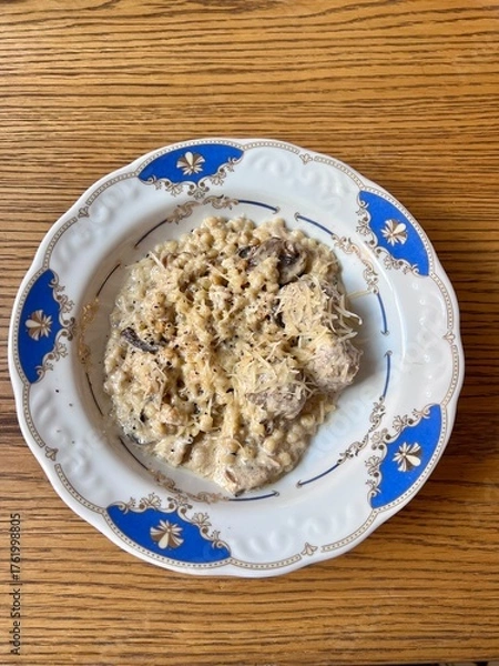 Obraz Ptitim pasta with chicken in a creamy sauce on a blue-rimmed plate lunch on the table