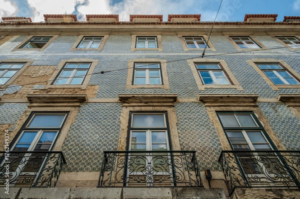 Fototapeta Weathered tiled façade of an old building in Lisbon, Portugal, showing ornamental ceramic patterns and signs of age and decay