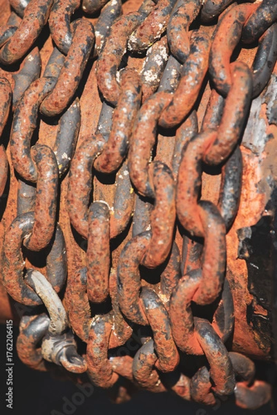 Fototapeta Close-up of heavy rusted metal chains in sunlight. Corroded industrial steel links with rough texture.