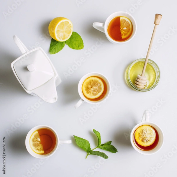 Fototapeta Cups of black tea with lemon and ceramic kettle, view from top