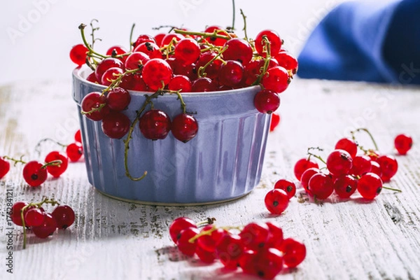 Obraz Red currant in a blue bowl on a wooden table