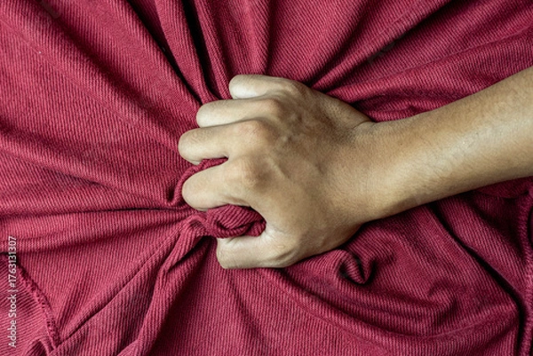 Fototapeta Close-up of a hand gripping red fabric, showing textile texture and material quality, symbolizing strength, tension, or fabric examination, top view, landscape