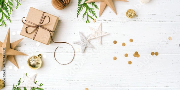 Fototapeta Festive Christmas background with gift box and Christmas decorations on white wooden table. Top view. Copy space for text.