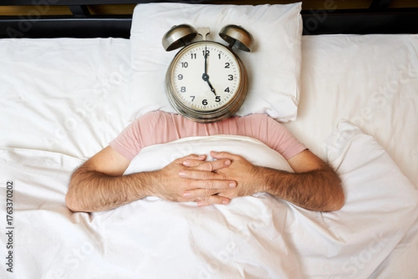 Fototapeta Man with alarm clock instead of head lying in bed. Morning concept