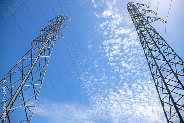 Obraz High voltage pylons against the blue sky and white clouds.