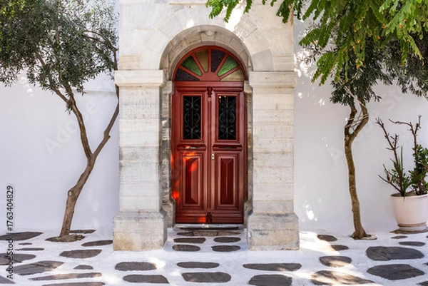Fototapeta white building with red door and vegetation. Greek island architectural design. atmospheric cityscape. ornamental entrance with red door. white architecture