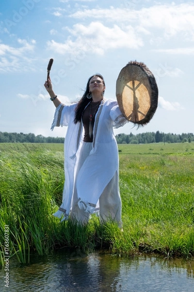 Fototapeta Shaman in the white dress drumming in the natural environment