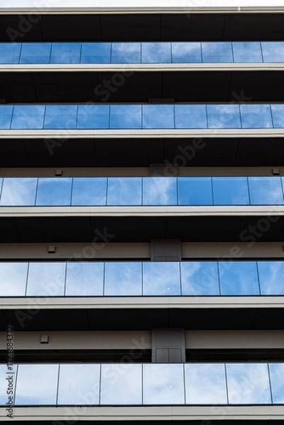 Fototapeta 反射するガラスと整然としたラインが美しい現代マンション外観
