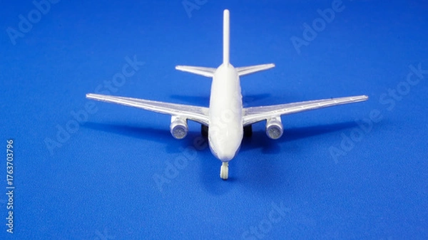 Fototapeta Model airplane on blue background, showcasing details of aircraft design and structure for aviation enthusiasts and hobbyists