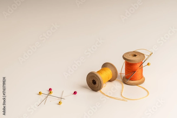Fototapeta Spools of thread and sewing needle on plain background symbolize craftsmanship and artistic creation.Сoncept of handmade, craft and artistic expression.