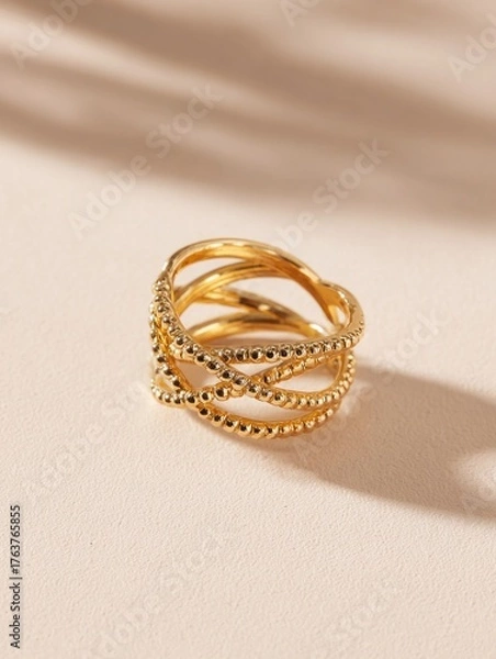 Fototapeta Intricate golden finger adornment features multiple crossing bands with detailed beading