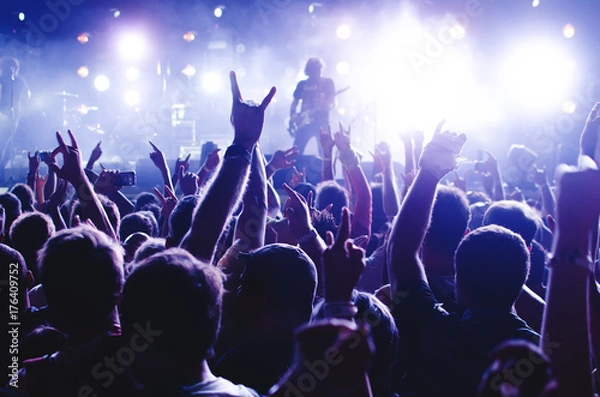 Obraz Tłum koncertowy. Sylwetki młodych ludzi przed jasnymi światłami scenicznymi. Zespół gwiazd rocka