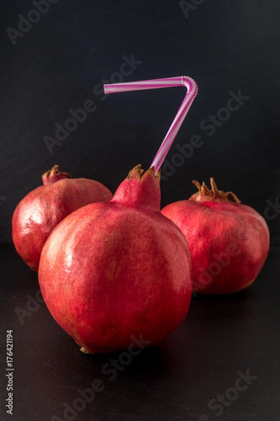 Fototapeta Fresh pomegranate with tube close up on black background