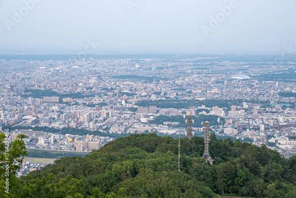 Fototapeta Panoramic view from Moiwa mountain, Cityscape view from green hill with communication towers in urban area at Sapporo, Hokkaido, Japan