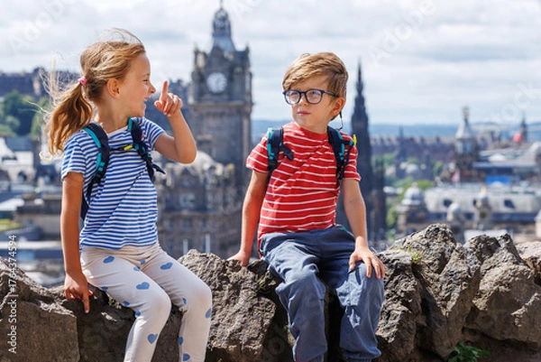 Fototapeta Two children with backpacks enjoy city views, smiling happily