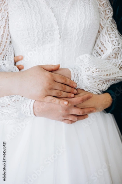 Fototapeta Tender moment — couple’s hands on the bride’s waist in a white lace dress. A symbol of love, care, and unity, reflecting purity and harmony of the wedding day.
