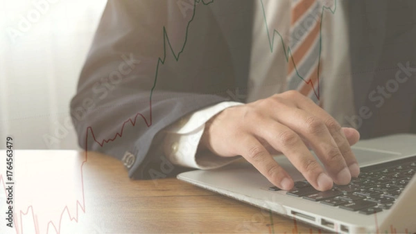 Fototapeta Businessman using laptop for financial analysis with stock market graph overlay, showing investment strategy and global economic trends in professional setting