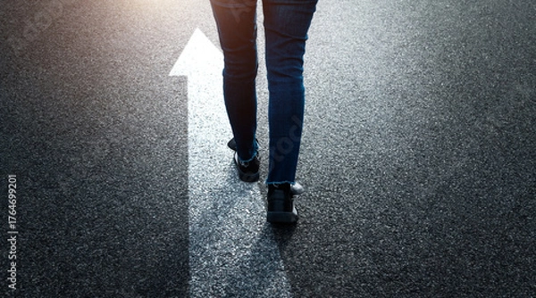 Obraz Woman standing on asphalt road with the arrow sign