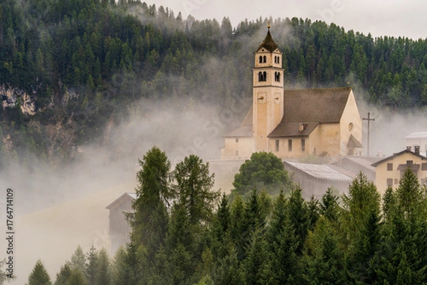 Fototapeta Beautiful mist-covered autumn landscapes in the Dolomites, Italy.- trees, mist, fog, and churches