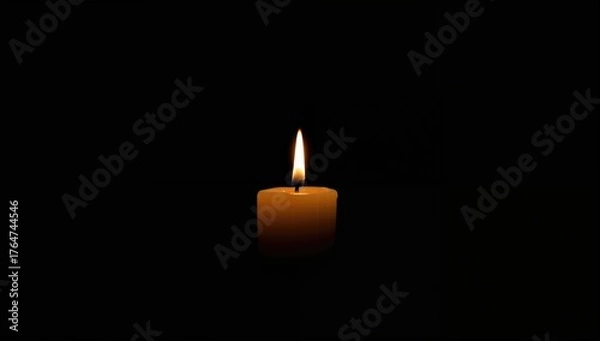 Fototapeta A single white candle flickers in the darkness, casting a gentle glow of hope