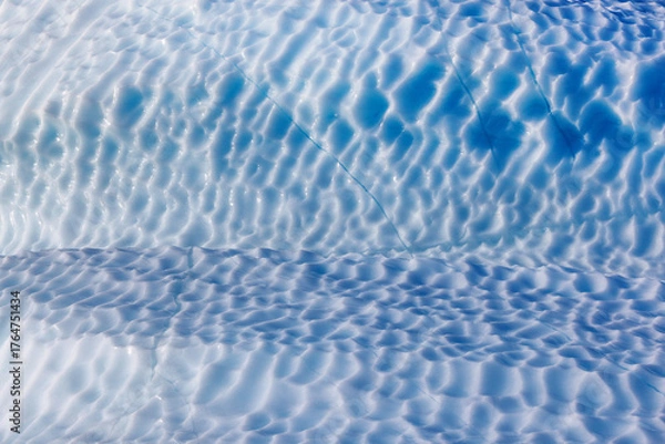 Fototapeta Dimpled surface of a giant blue iceberg in Kjerulf fjord, Northeast Greenland National Park. Abstract background texture of weathered ice.