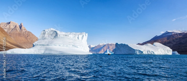 Fototapeta Kjerulf fjord, Northeast Greenland National Park. Known as the Iceberg Graveyard, because they are driven in by wind and currents and become stranded. A small boat gives scale to the giant icebergs.