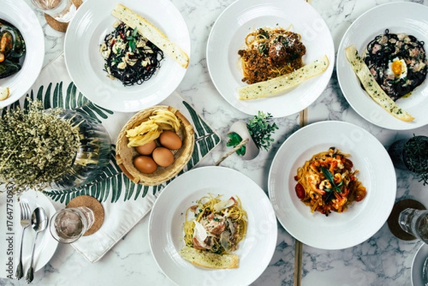 Fototapeta Various delectable pasta dishes beautifully presented on a marble table, a feast for the eyes and the palate