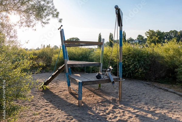 Fototapeta Playground with a climbing frame on a gravel ground. Empty leisure activity object in a public area in Germany. Child-friendly building out of wooden material.