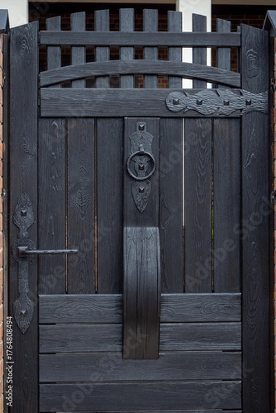 Obraz Black wooden gate with metal hardware, entrance to private property. Use in architecture, fencing systems, security design and urban landscape. Real photo