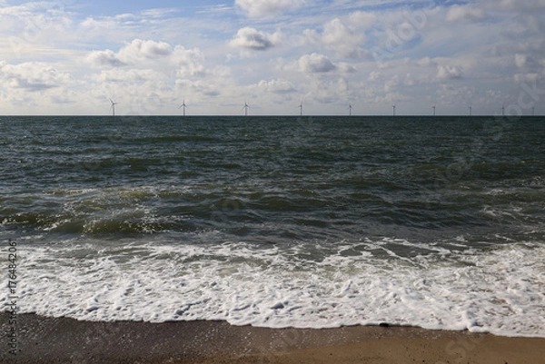 Fototapeta Landscape photo with a view of the waves of the North Sea and windmills in the background near Bovbjerg Lighthouse in Lemvig, Denmark	
