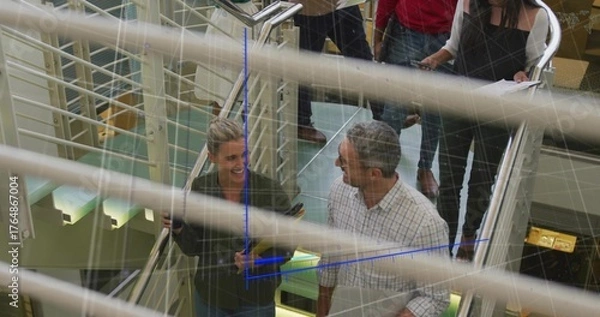 Fototapeta Six professionals ascending metal glass staircase in office atrium, with laptops and document tubes