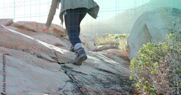 Fototapeta Climbing mid adult hiker ascending weathered rock in desert canyon, with backpack and hiking boots