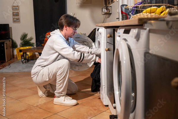 Obraz jeune homme encore adolescent remplissant un sèche linge de vêtements lavés