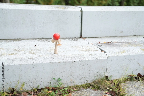 Fototapeta A small red ball is sitting on a cement step