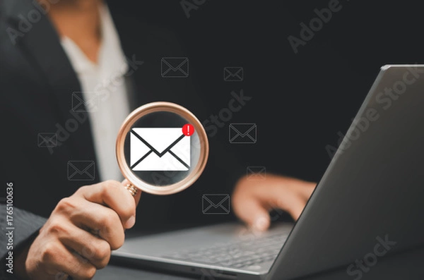 Fototapeta Businessman using a magnifying glass sending newsletters and engaging contacting clients or customers and networking online. Business communication and marketing networking online.