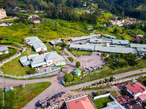 Fototapeta An aerial view of a public building complex, in the mountain town of Maubisse, Ainaro, Timor-Leste. The facility is set amidst a lush green highland landscape.