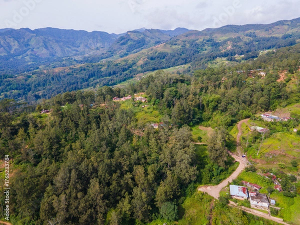 Fototapeta A stunning aerial view of Maubisse village in the highlands of Ainaro, Timor-Leste. Houses are scattered across the ridges and valleys, surrounded by a vast, green mountain landscape