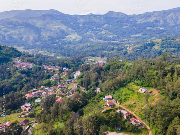 Fototapeta A stunning aerial view of Maubisse village in the highlands of Ainaro, Timor-Leste. Houses are scattered across the ridges and valleys, surrounded by a vast, green mountain landscape