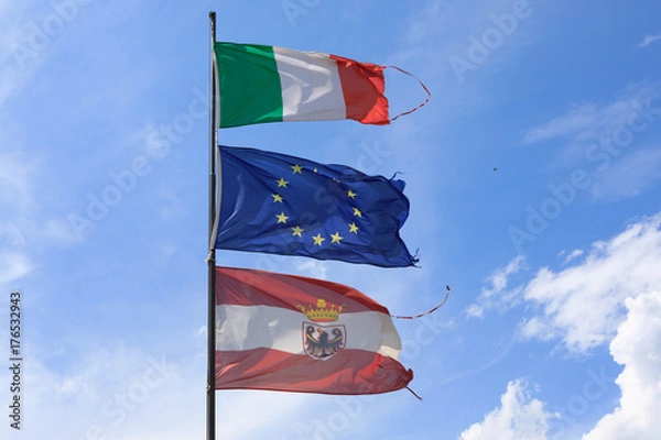 Obraz The Italian, Austrian and Eu flag blows in the wind at Lake Garda, Italy.