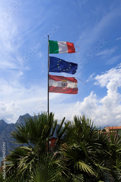 Obraz The Italian, Austrian and Eu flag blows in the wind at Lake Garda, Italy.