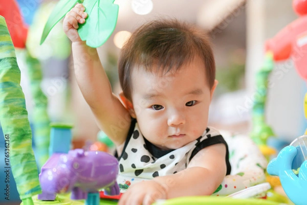 Obraz A baby is playing with a toy elephant. The baby is holding the elephant toy in its hand