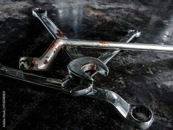 Fototapeta Worn Mechanic's Wrenches Scattered on a Dark, Grungy Workbench. Depicting repair, hard work, and the mechanical industry.