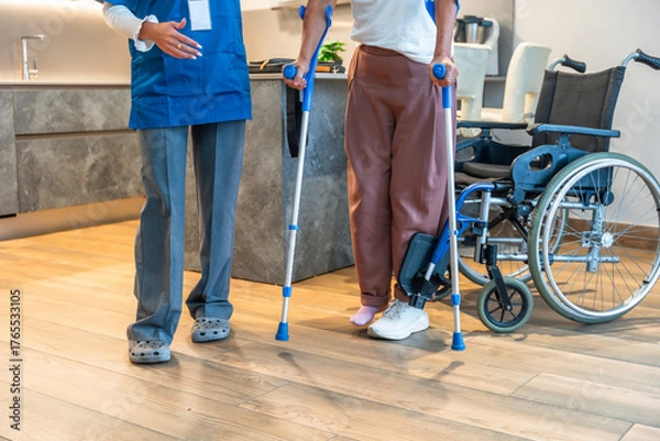 Fototapeta Nurse assisting patient with crutches during physiotherapy rehabilitation