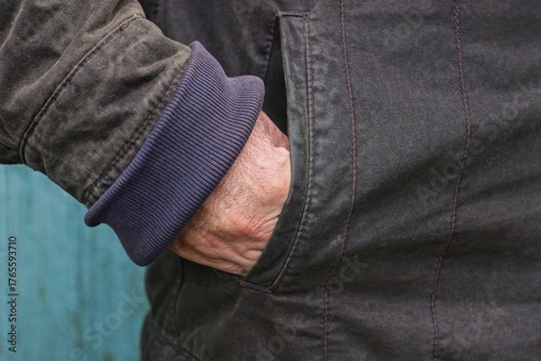 Fototapeta part of black winter jacket with hand in pocket on one man on winter street