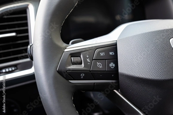 Fototapeta Audio volume, cruise control and various other buttons on a new car's leather wrapped steering wheel. Close up shot, no people