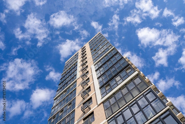 Obraz Modern residential building facade with glass windows and concrete panels against blue sky, perspective from below. For architecture, construction, building materials, real estate projects. Photo